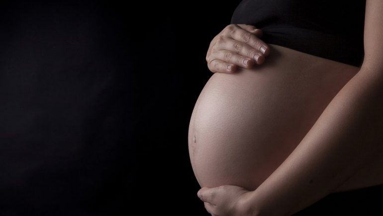 Midsection Of Pregnant Woman Touching Her Belly, Studio shot