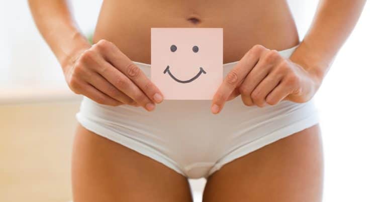 Young woman holding paper with smile mark over her stomach. Health hygiene sexual education concept.
